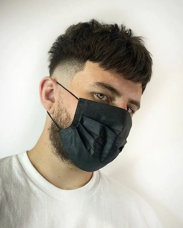 Fluffy texture mens hairstyle on a guy in a mask with a beard
