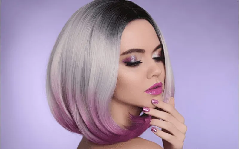 Gal with an ombre bob haircut and purple lipstick holds her chin mysteriously