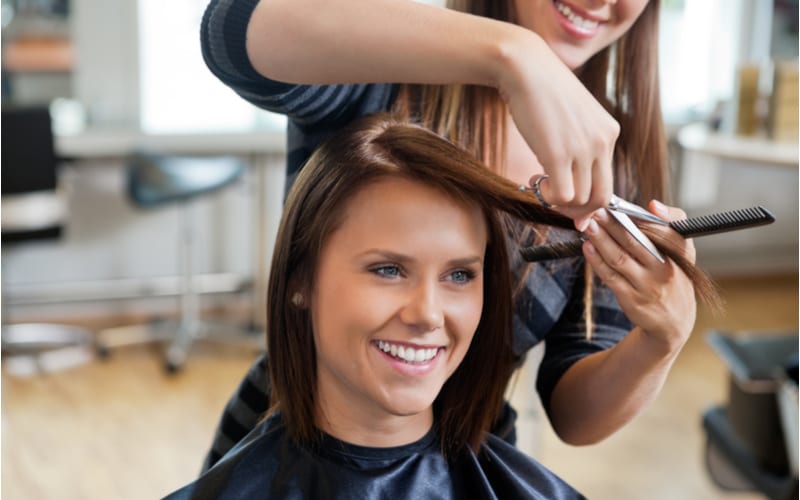 Attractive young woman is spending time in beauty salon. Paying via credit card