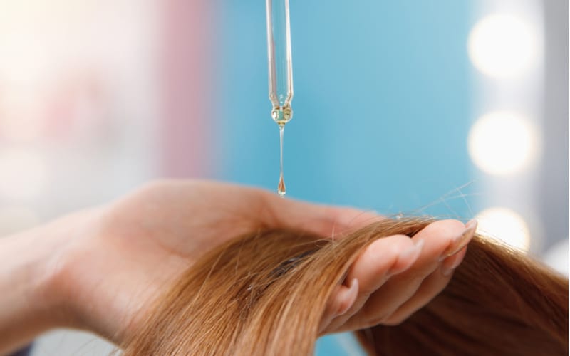 Close-up drop of oil restore and recovery hair is applied to head bulbs. Concept hairdresser spa salon as a piece on hair straightening cost