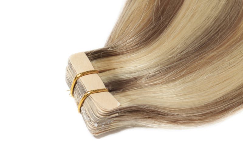 To help illustrate the cost of hair extensions, close up of glue tape of straight brown mixed blonde tape in remy human hair extensions