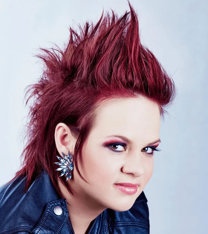 Lady with a thick red mohawk gazes out of the corner of her eye seriously