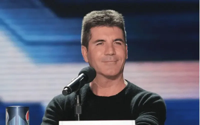 Simon Cowell of The X Factor stands in front of a microphone for a piece on bad haircuts