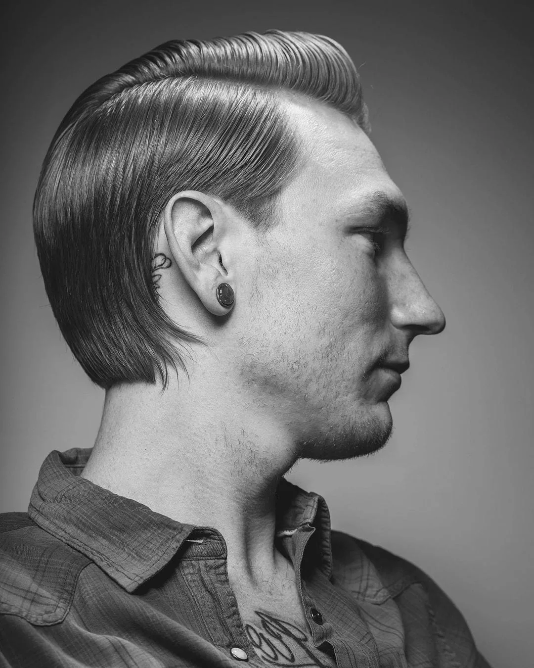 Man with a slicked back mullet haircut and a hard part that's etched into his head in black and white
