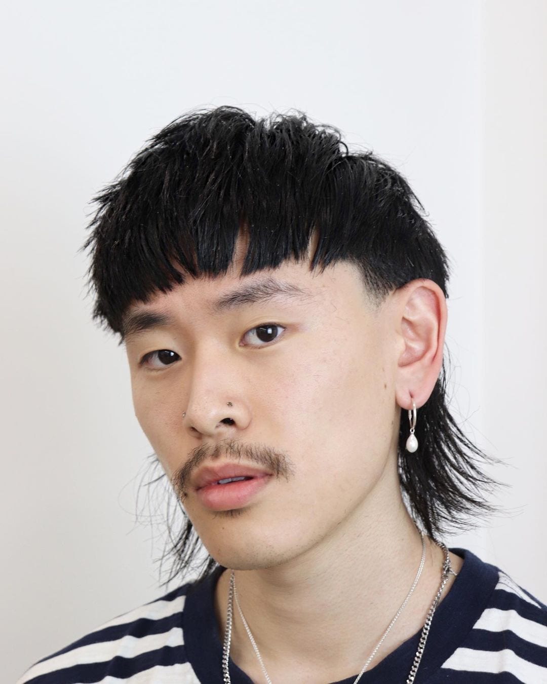 Asian man with a bowl cut mullet and a nasty looking dirty stache and longer earrings