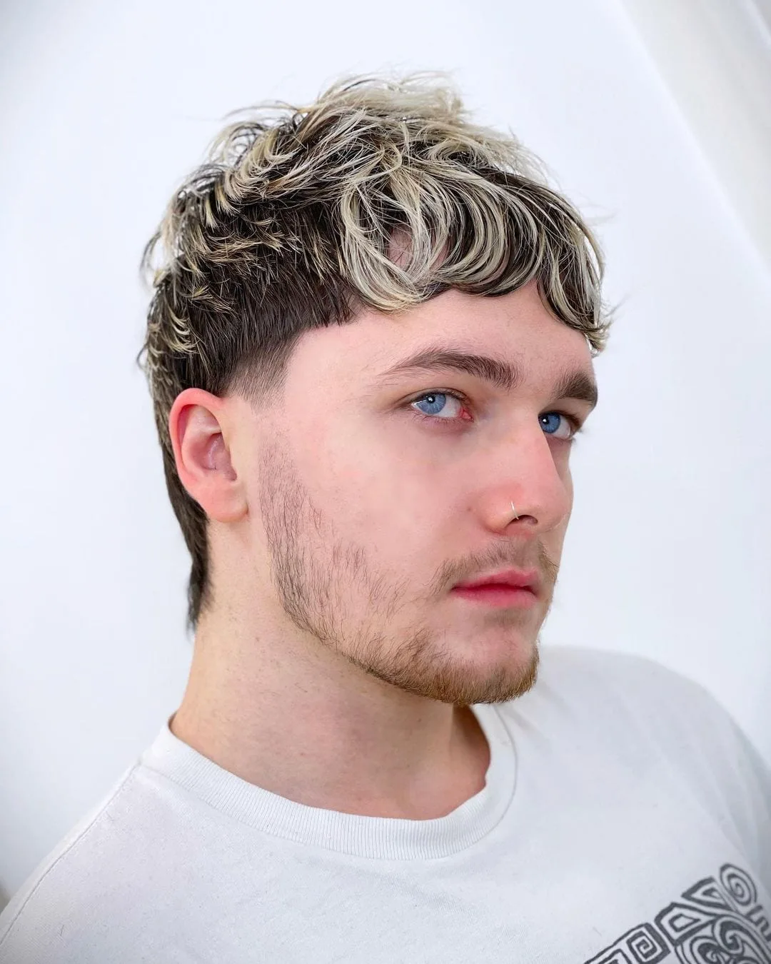 Man with steeley blue eyes and a mullet haircut and bleached top