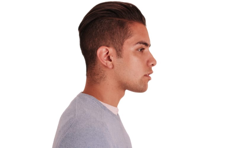 Side view of Hispanic man with cool undercut standing with white background