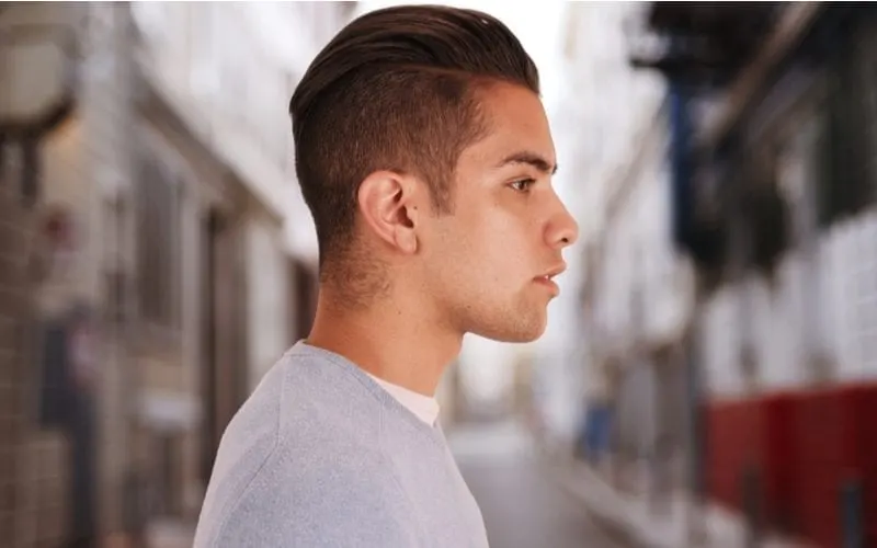 Cool young Mexican man with a slicked back undercut in the middle of a city alleyway