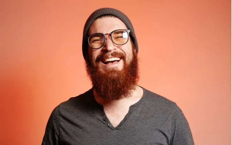 Close up portrait of happy smiling bearded hipster man with eyeglasses and looking confident at the camera