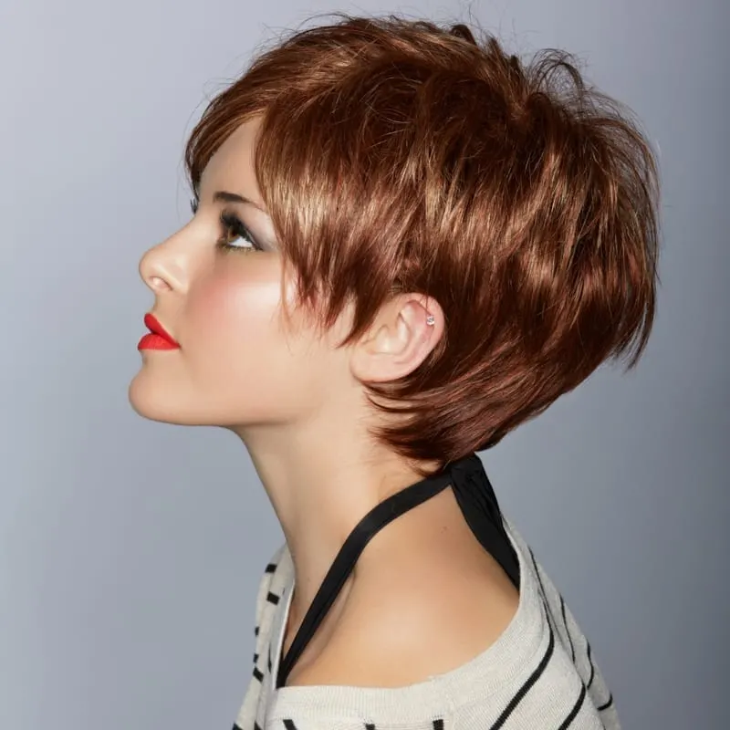 profile of a beautiful woman with red lips and short feathered red hair in modern bob over studio background