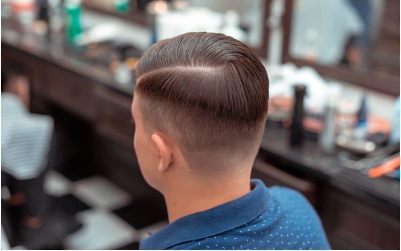Men's haircut and styling in barbershop. Stylish Haircut with short sides and a long top with a defined part