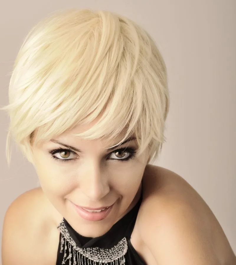 Beautiful young woman with short pixie light blond hair looking at camera and smiling