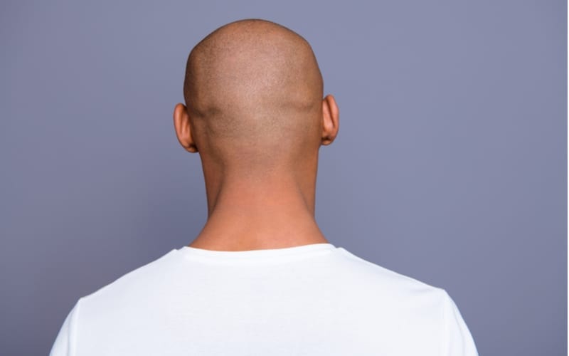 Close up back behind rear view photo dark skin he him his man turned to empty space distracted unrecognizable groomed shaved head wearing white t-shirt outfit clothes isolated on grey background
