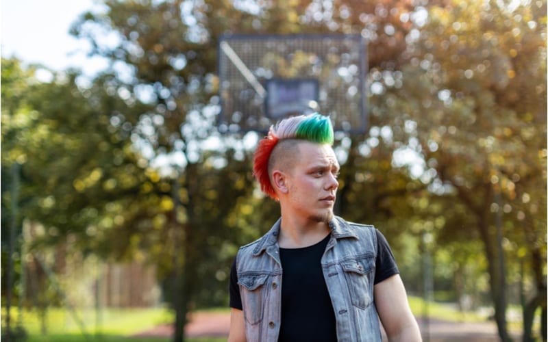 Portrait of a cool young man with pink mohawk as another example of a teen boy haircut