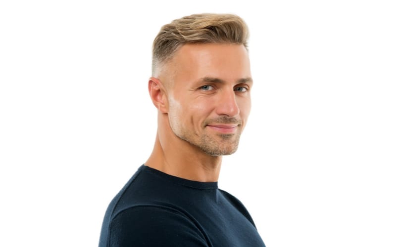 Man with a nice short side haircut with a long top smiling against a white backdrop