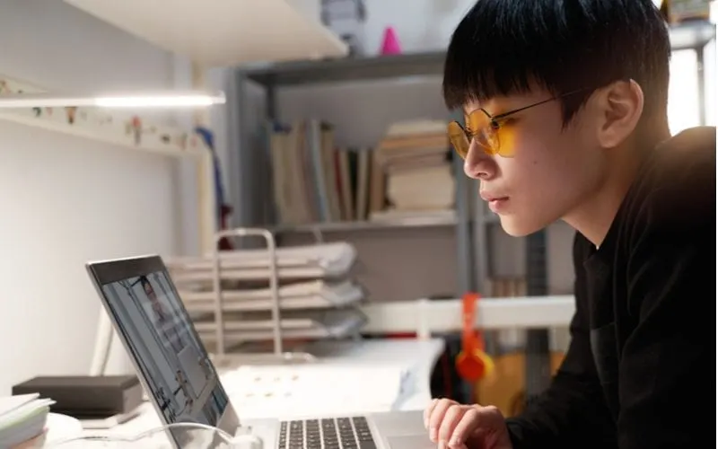 Young asian kid looking at a laptop and wearing a two block haircut
