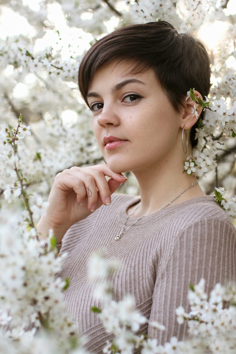 Girl with a pixie cut standing in a field of flowers