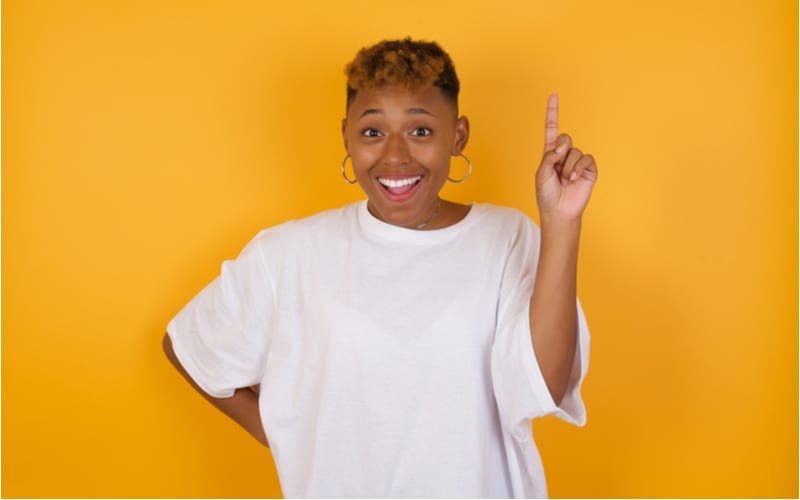 Young african american woman with a short haircut wearing casual clothes holding finger up having idea and posing