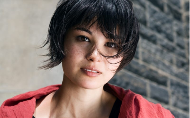 Closeup portrait of a beautiful young asian japanese girl woman with freckles with black short pixie haircut in red shawl scarf looking straight into the camera
