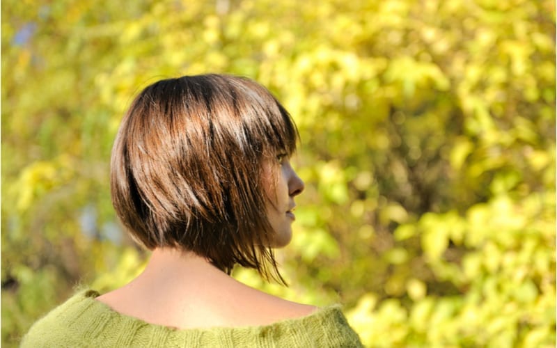 Beautiful young woman wearing short shag hairstyle autumn outdoor, focus on a hair.