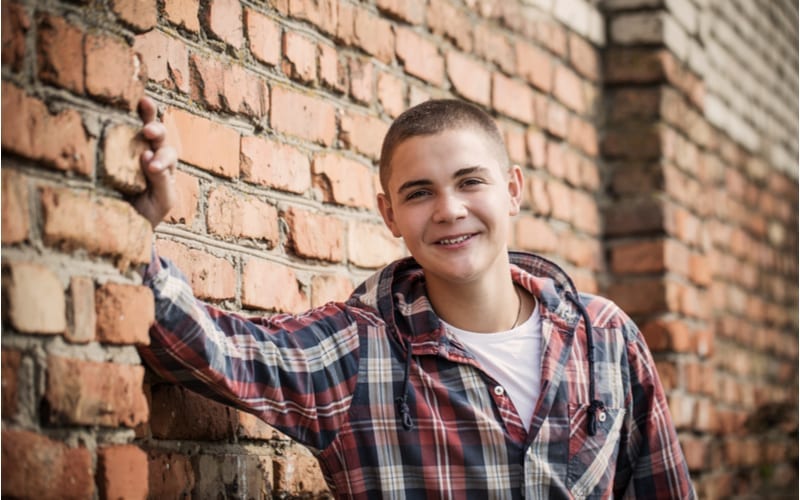 teen boy by brick wall with a nice looking teen boy haircut that is an undercut