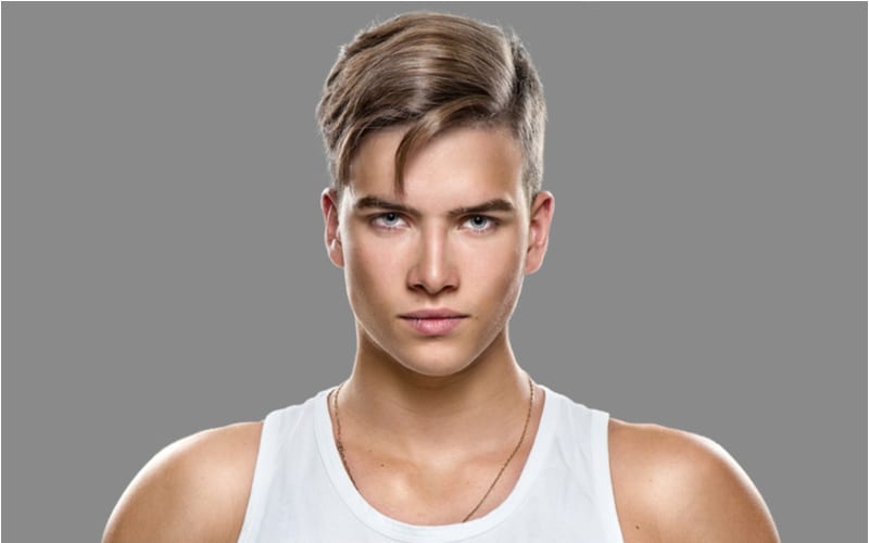 Handsome Athletic young man isolated on grey background. Muscular teenage guy portrait with an average teen boy haircut