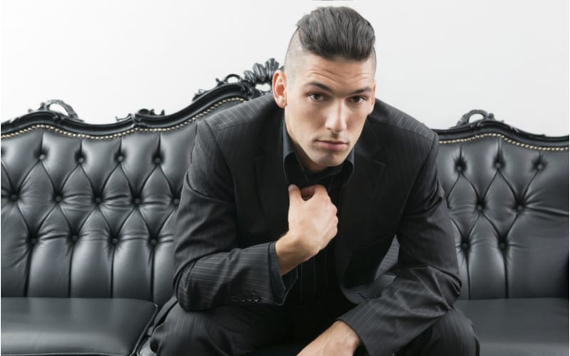Young man in business suit and undercut sitting on leather sofa