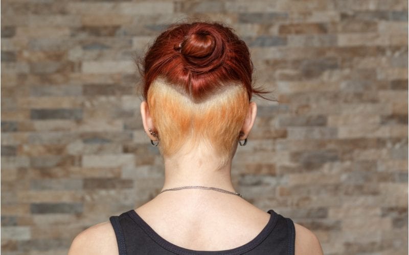 Young person with colored hair cut into a high fade with a small and tight bun which is an unprofessional hairstyle