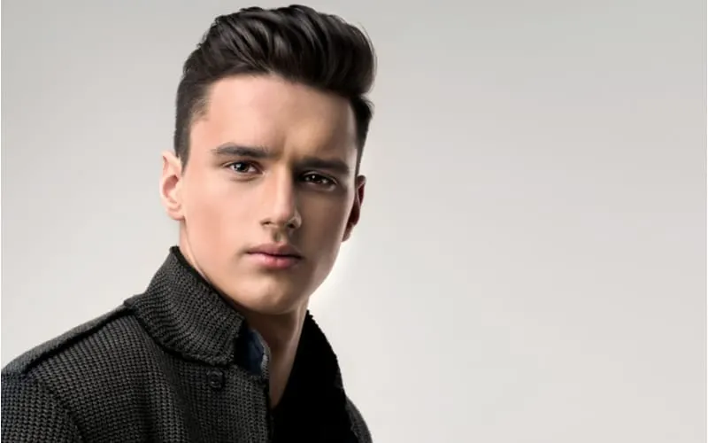 Fashion portrait of a handsome man with trendy hairstyle in a stylish jacket and a short sides long top hairstyle