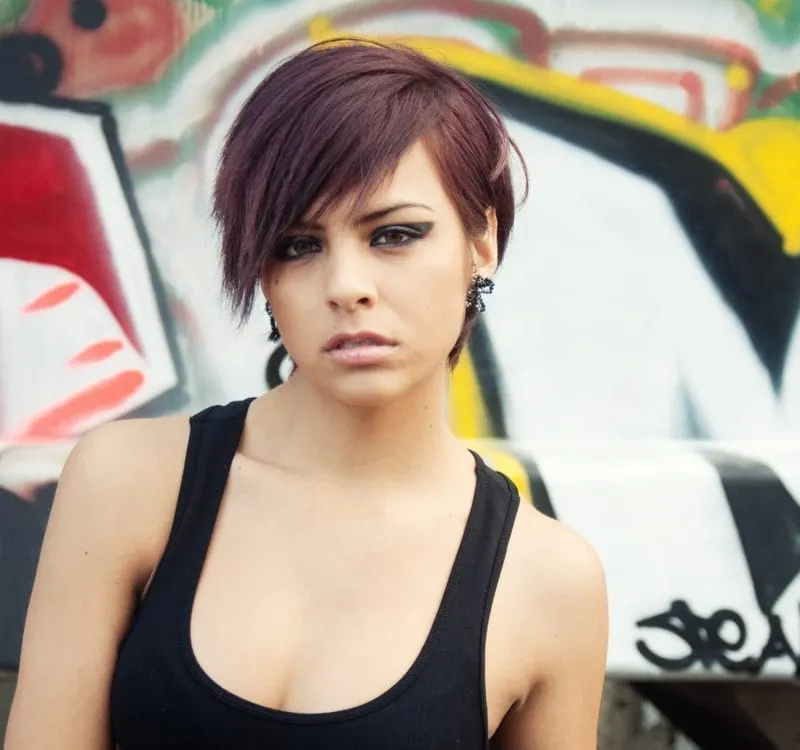 Young woman with short hair posing beside graffiti background
