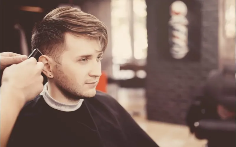 Hip young guy with a long top short sides hairstyle sitting in a barber chair