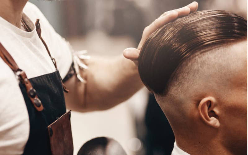 Close-up of barber shop does haircut undercut for man. Concept barbershop. Soft focus.