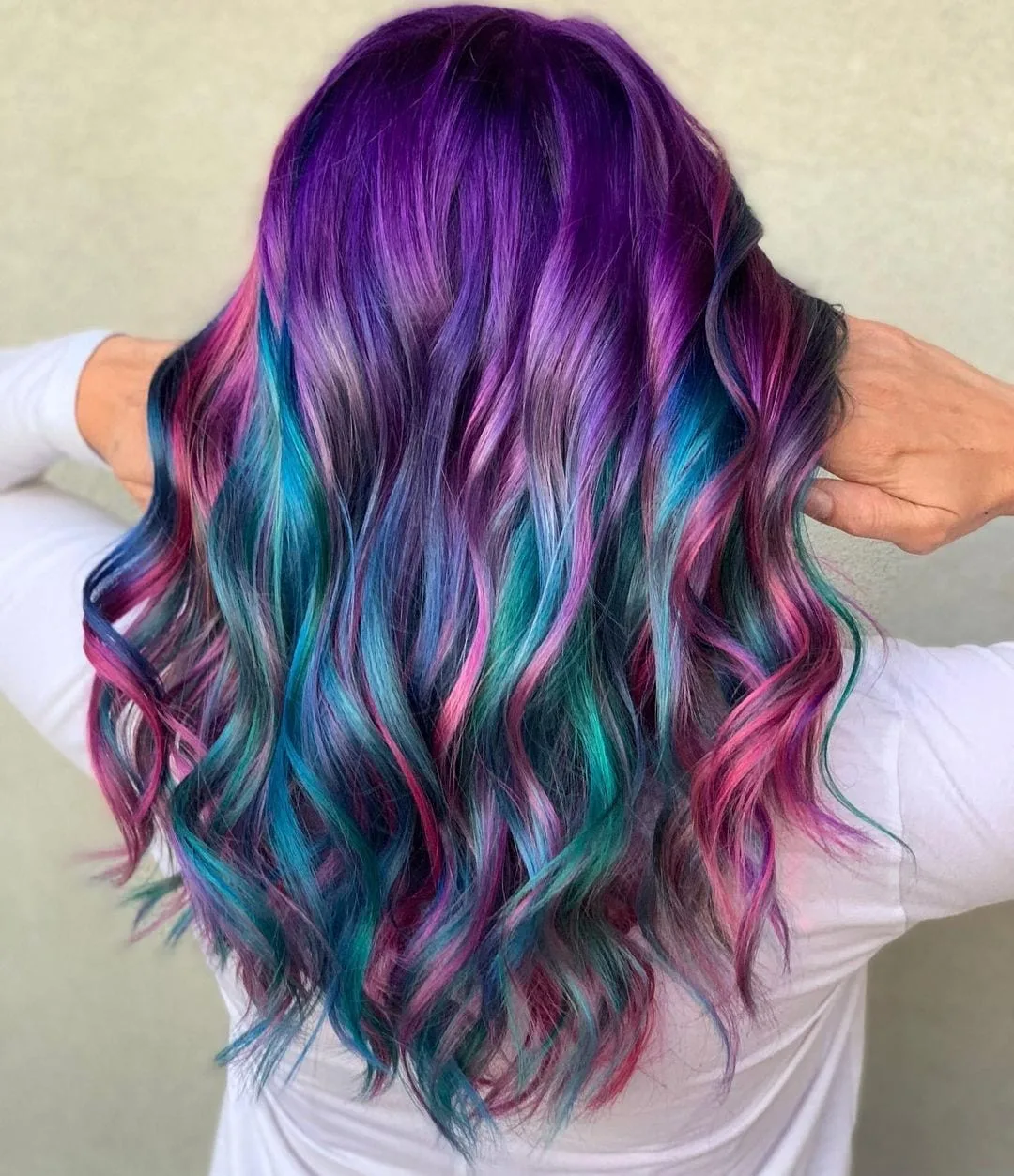 Woman with purple and pink galaxy hair holds it at the base