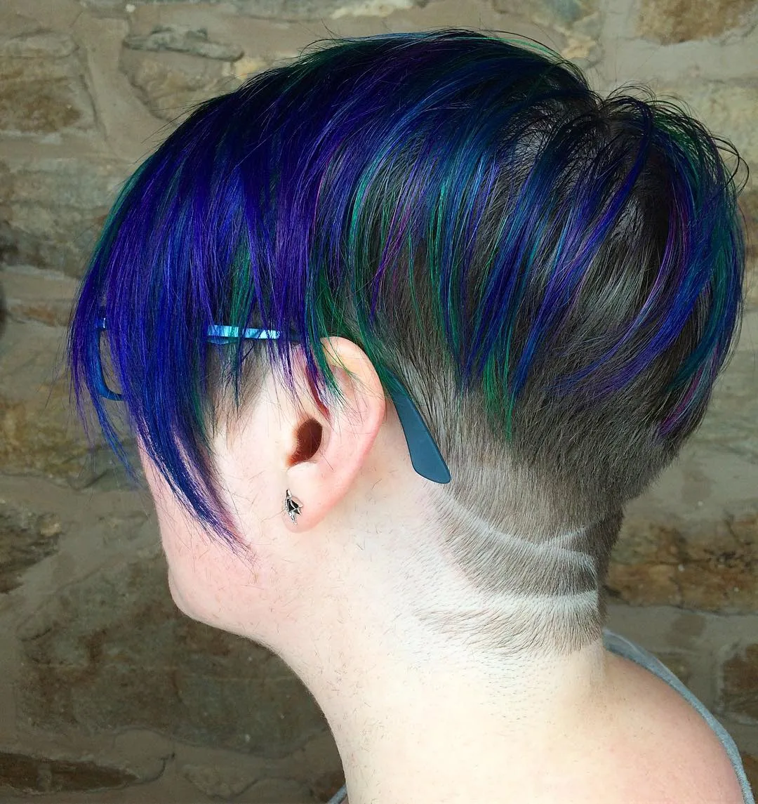 Woman with a shaved undercut and glasses with dark blue hair on top which is kept long