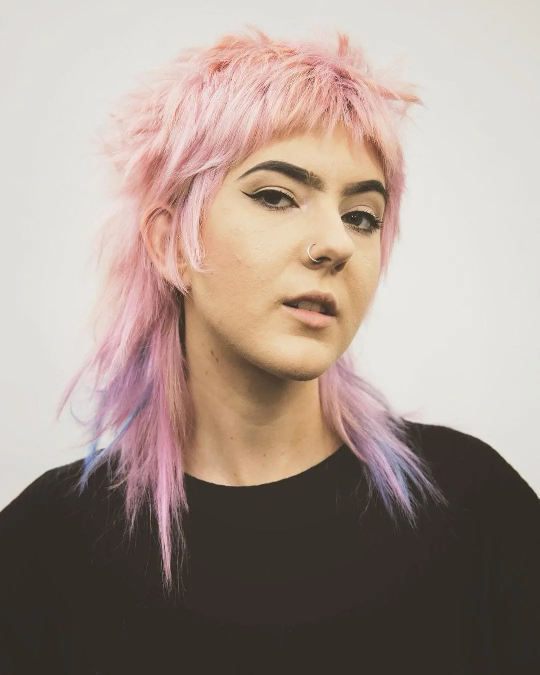 Woman with a mullet that is light pink and blonde with purple galaxy hair tips