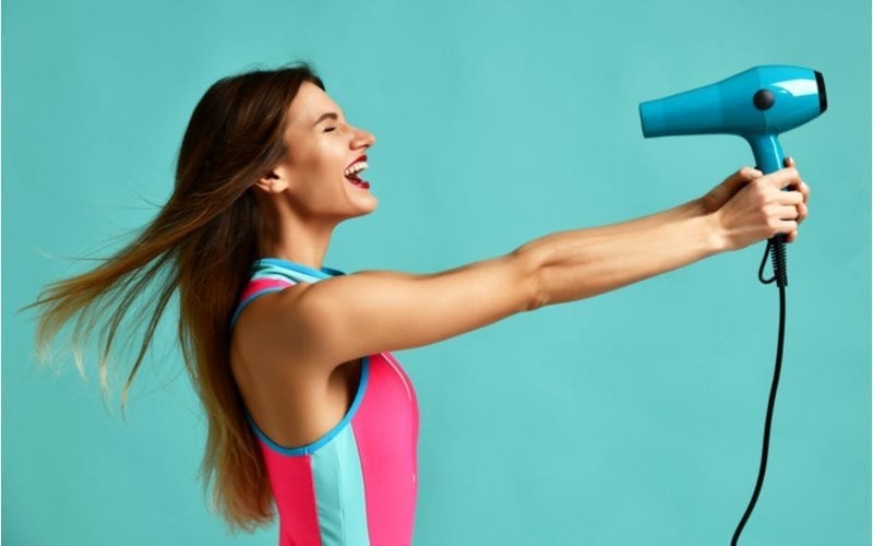 Attractive brunette woman holding her hair dryer away from her head because it's the best and very powerful
