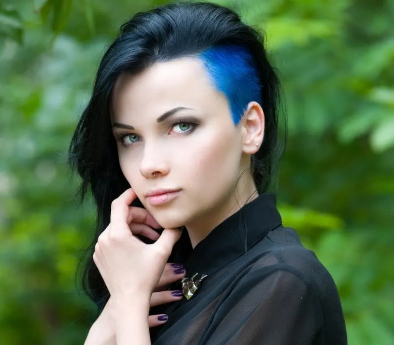 Urban punk girl with a shaved hairstyle for women that's half-shaved and blue on the side with a long top