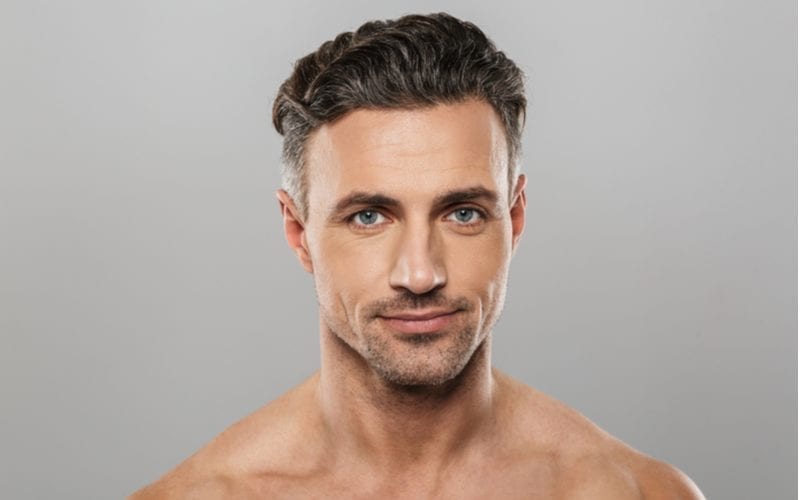 To help you decide which haircut you should get, a Guy with steel gray eyes and slicked back hair without a shirt looks at the camera