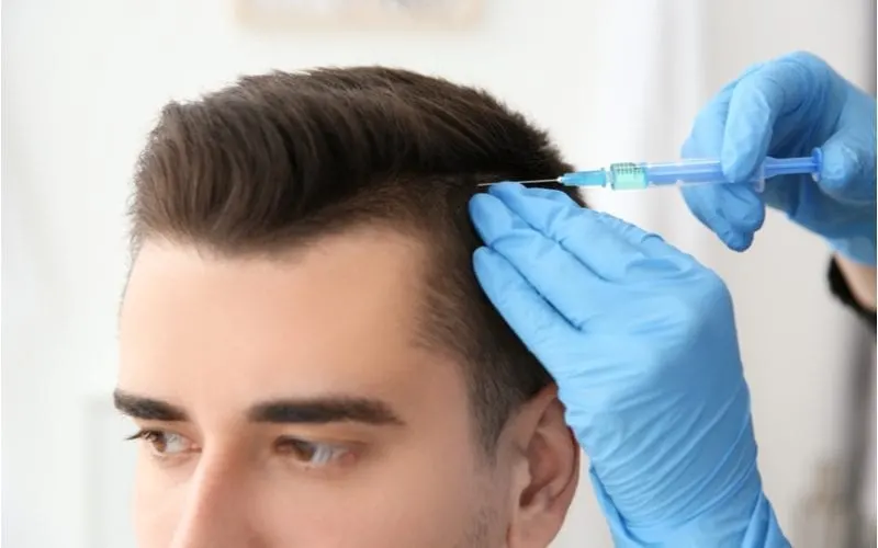 Guy getting his hair numbed for a piece on hair transplant cost