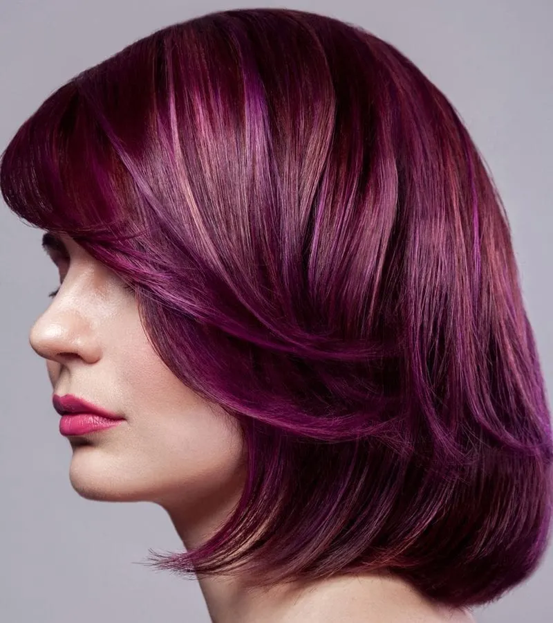 Woman with light purple-red hair looks straight ahead