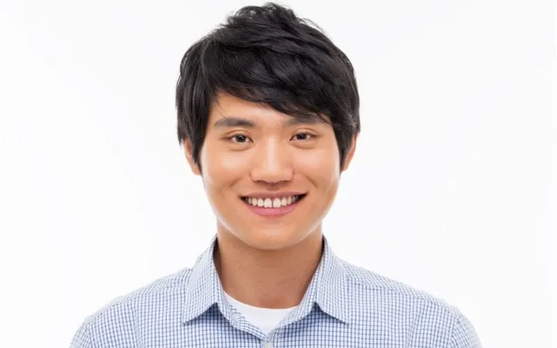Man with a gingham blue button up rocks a standard asian man hairstyle and smiles in a studio