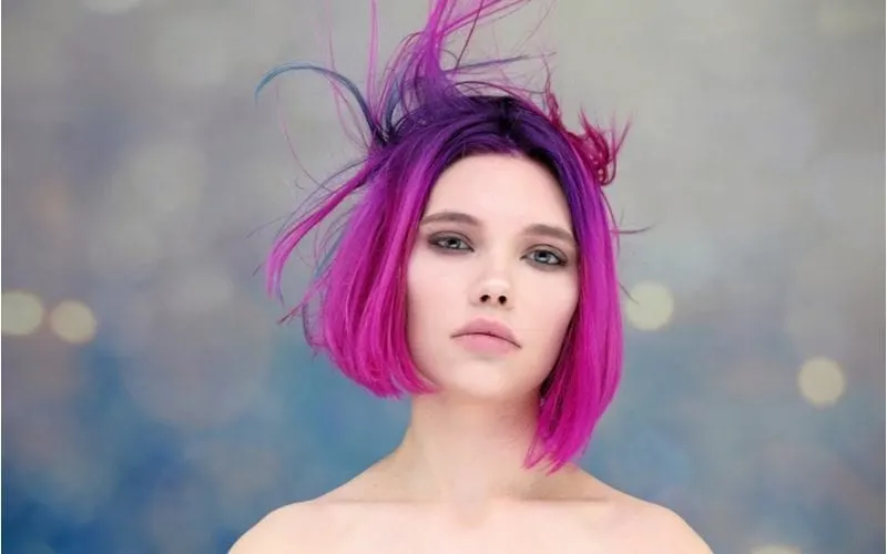 Young woman with an e-girl haircut that is pink and purple and blows up in the wind