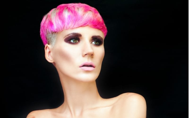 Drop mushroom bowl cut that is colored spotty pink on a woman with a ton of makeup on