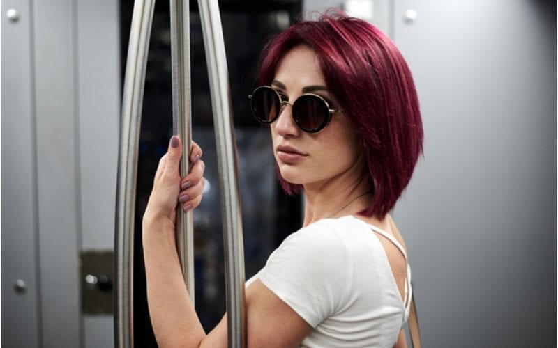 Woman with dark glasses on a subway and wearing burgundy hair