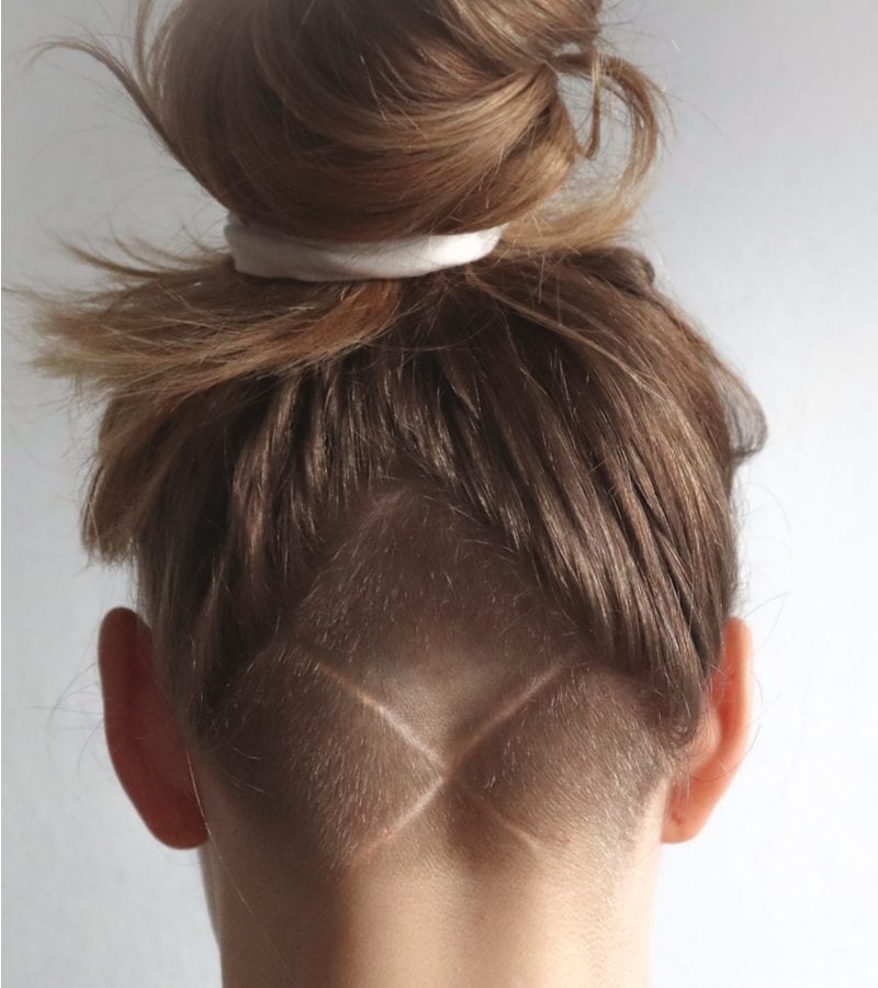 A pointed undercut nape with long hair on top in a messy bun