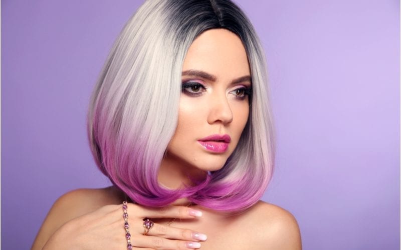 Woman wish fuscia hair wears purple lipstick and no shirt