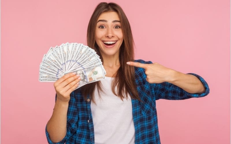 Woman holding up cash she saved using Great Clips Coupons