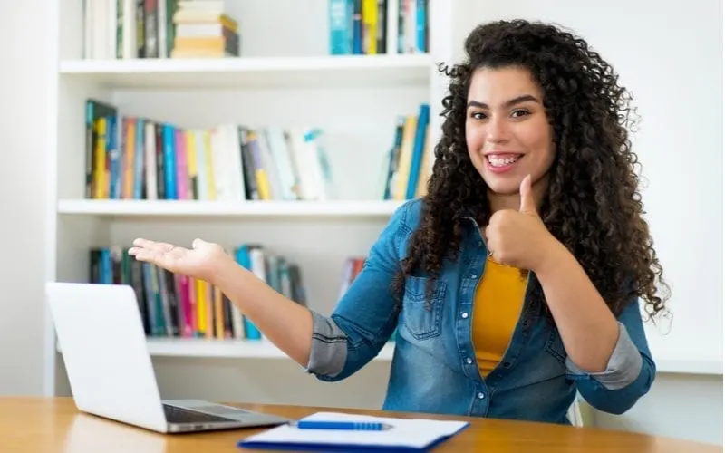 Curly Latina Hairstyle on a pretty young woman sitting in front of a laptop