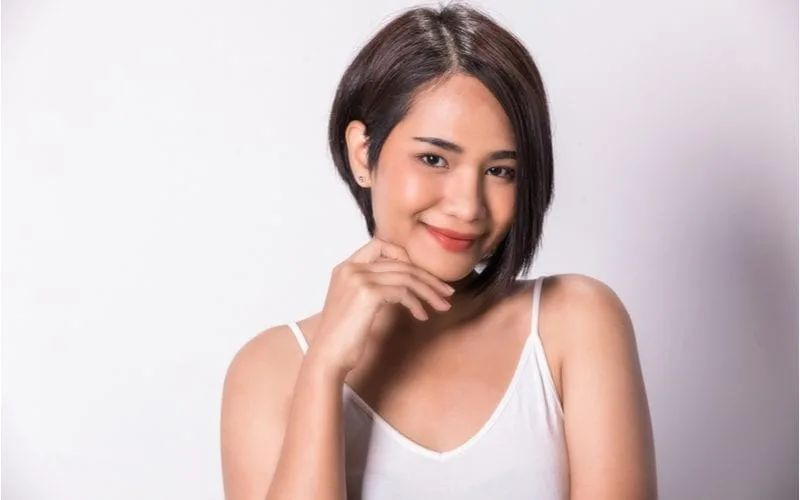 Asian woman with a white camisole and an asian short hairstyle looks up
