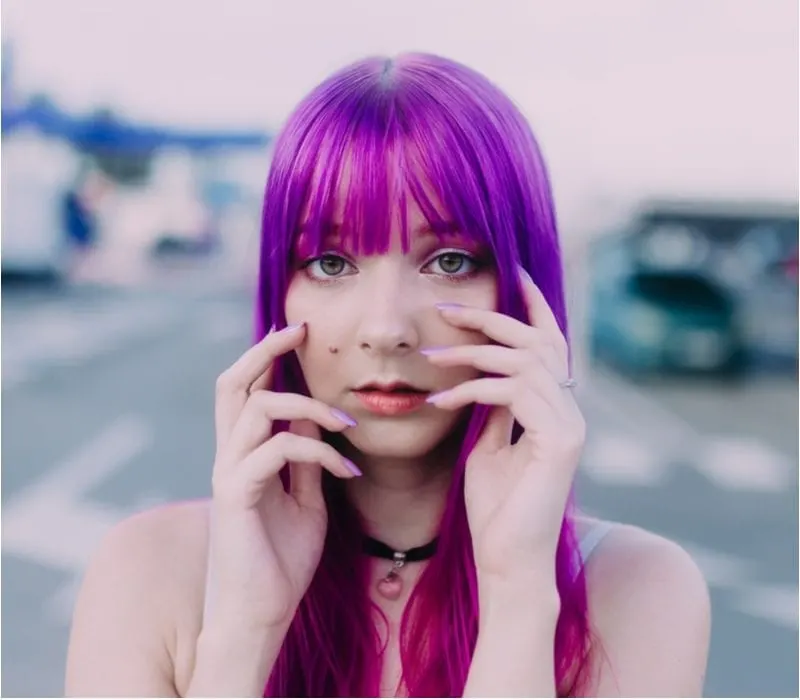 Girl with purple hair holds her hands up to her face